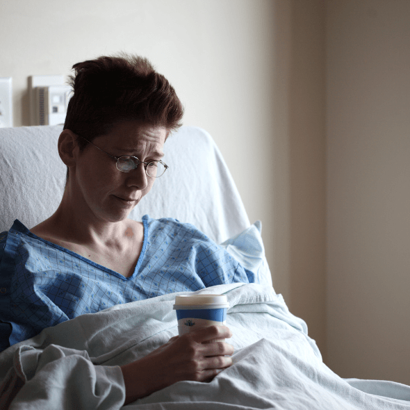Paciente em cama de hospital com um copo na mão